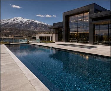 Modern custom shotcrete pool beside a glass commercial building with mountain views.